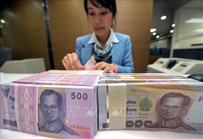 Kiểm đồng baht tại một ngân hàng ở Bangkok, Thái Lan. Ảnh: AFP/TTXVN
