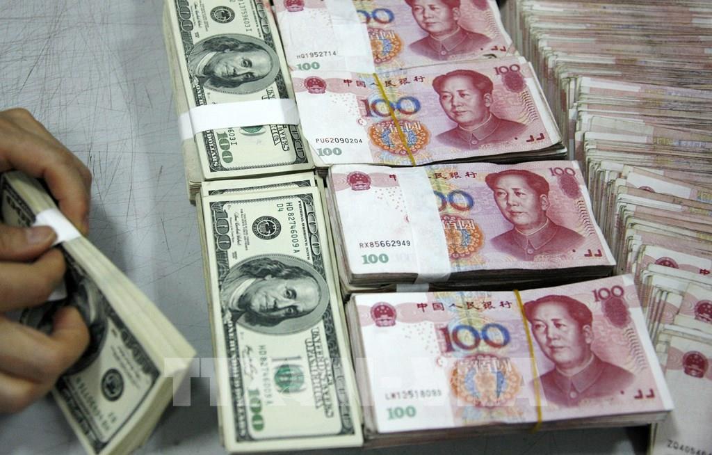 Nhân viên kiểm đồng USD (trái) và đồng NDT tại một ngân hàng ở tỉnh An Huy, Trung Quốc. Ảnh: AFP/TTXVN