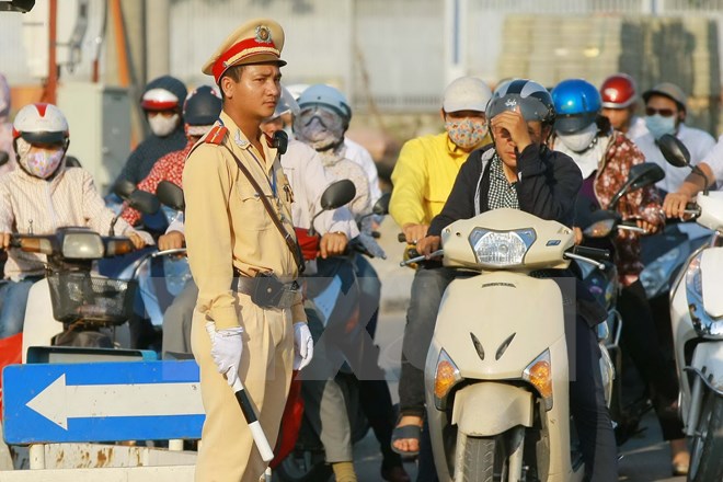 Cảnh sát giao thông và người tham gia giao thông dưới cái nắng nóng lên tới 40 độ C ở Hà Nội. (Ảnh: Doãn Tấn/TTXVN)