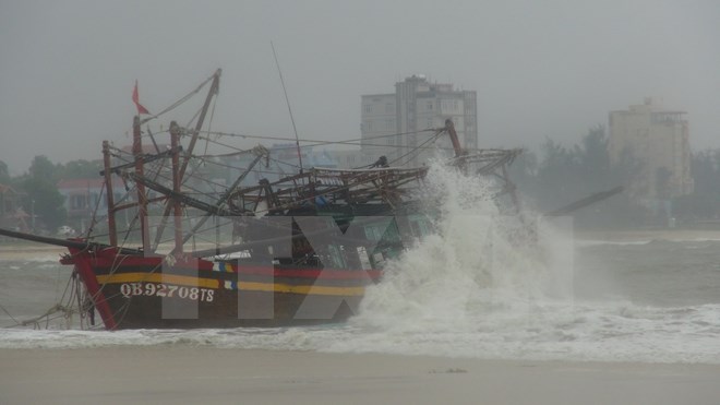 Một tàu cá bị mắc cạn, có nguy cơ bị sóng đánh chìm tại cửa biển Nhật Lệ, thành phố Đồng Hới, tỉnh Quảng Bình. Ảnh: TTXVN