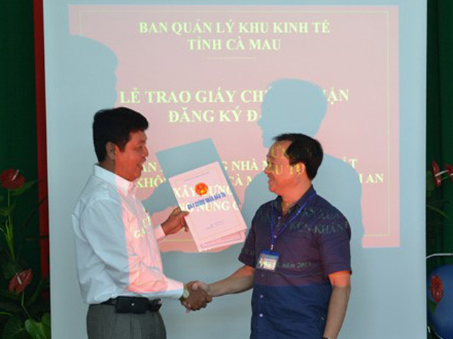 Ông Nguyễn Minh Ái, Trưởng BQL Khu kinh tế Cà Mau (bên phải) trao giấy chứng nhận cho nhà đầu tư