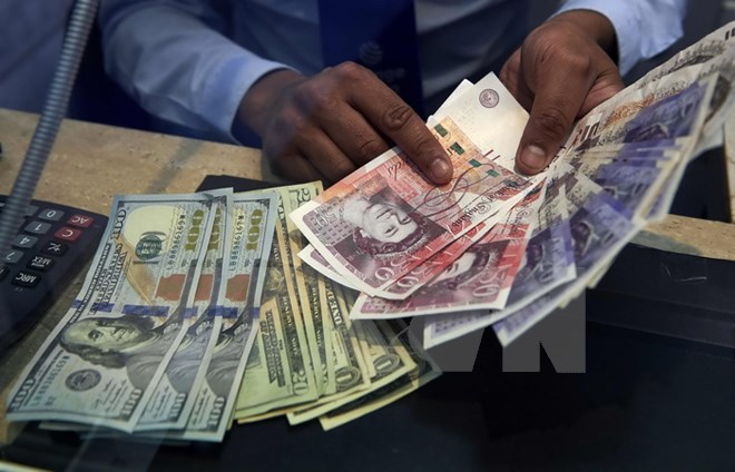 Đồng bảng Anh (phải) và đồng USD tại một cửa hàng ngoại hối ở London (Anh). Nguồn: AFP/TTXVN