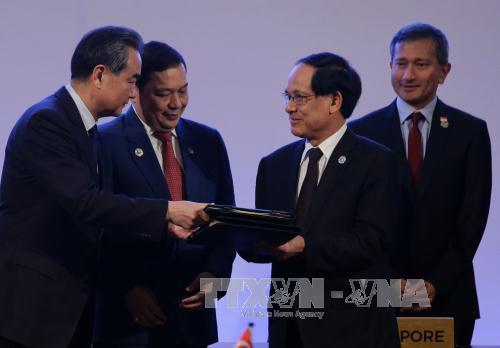 Bộ trưởng Ngoại giao Trung Quốc Vương Nghị (trái) và Tổng thư ký ASEAN Lê Lương Minh (thứ 2, phải) trao đổi văn kiện sau lễ ký Biên bản ghi nhớ về việc thành lập Trung tâm ASEAN - Trung Quốc ngày 6-8. Ảnh: AFP/TTXVN
