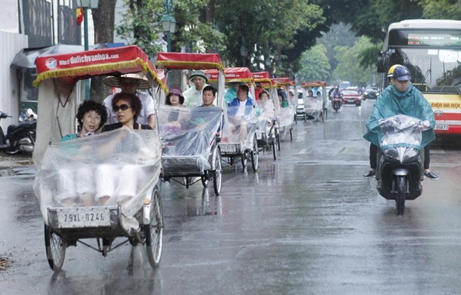 Các xe xích lô chở khách du lịch được che chắn cẩn thận tránh cơn mưa. (Ảnh: Lâm Khánh/TTXVN)