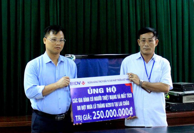 Ông Phan Quang Hưng, Phó Giám đốc BIDV Lai Châu  trao biển tượng trưng  số tiền 250 triệu đồng cho đại diện  Sở Lao động - Thương binh và Xã hội tỉnh Lai Châu