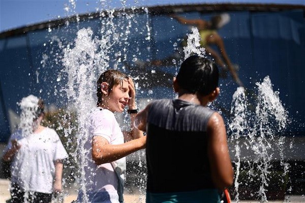Trẻ em tránh nóng tại vòi phun nước ở Melbourne, Australia, ngày 24/1. (Nguồn: AFP/TTXVN)