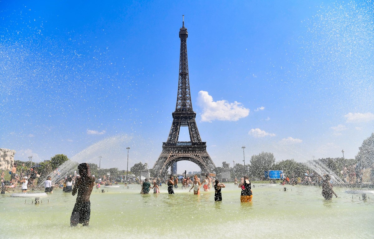 Người dân tránh nóng bên vòi phun nước tại Paris, Pháp. (Ảnh: THX/TTXVN)