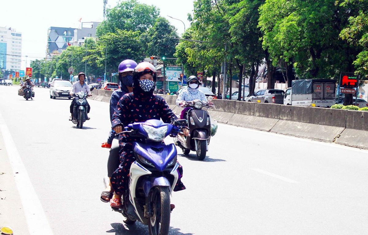 Người dân đều trang bị khẩu trang và mặc áo chống nắng kín khi di chuyển trên đường trong thời tiết nắng nóng. (Ảnh: Tá Chuyên/TTXVN)