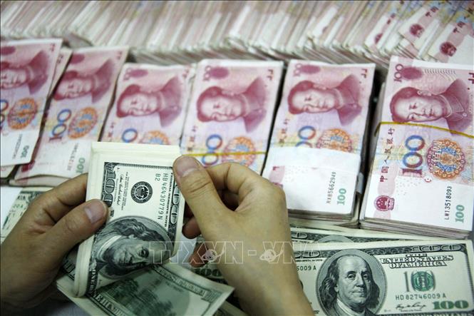 Nhân viên kiểm đồng USD và đồng NDT tại một ngân hàng ở tỉnh An Huy, Trung Quốc. Ảnh: AFP/TTXVN