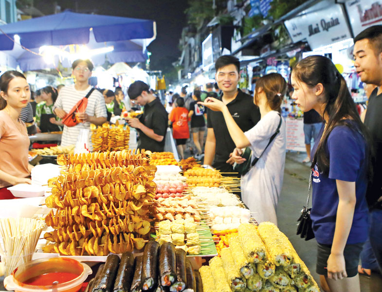 Du khách chọn món ăn tại chợ đêm khu phố cổ (quận Hoàn Kiếm, Hà Nội). Ảnh: Hồ Hạ