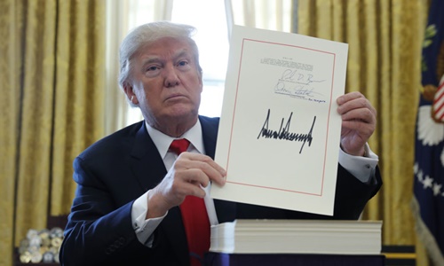 Tổng thống Mỹ Donald Trump cầm bản cải cách thuế với chữ ký của ông tại Phòng Bầu dục, Nhà Trắng, ngày 22/12. Ảnh: VnEpress/Reuters