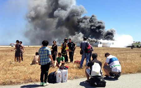 Các hành khách quan sát từ xa chiếc máy bay bốc cháy.